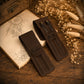 Two dark brown leather pen cases on a rustic wooden table, one closed with the name 'Julia' and one open holding two black pens, both with 'N.K.