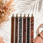 Set of patterned straps on a marble surface with dried flowers and a handbag.
