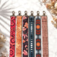 Set of six patterned lanyards on a light background with dried flowers.