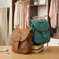 Two bags, one brown and one green, on a wooden surface with a clothing store in the background.