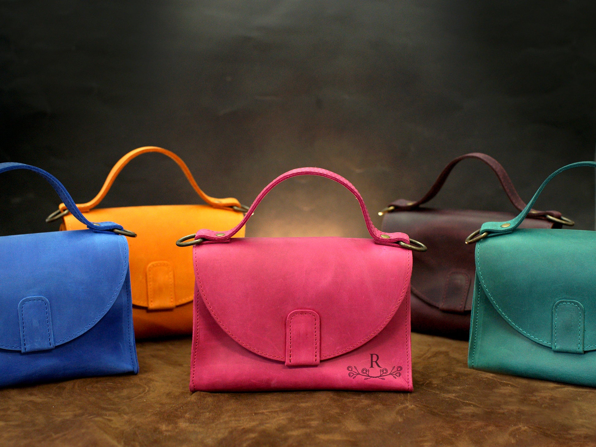 Multiple leather handbags with monogram initials on textured surface
