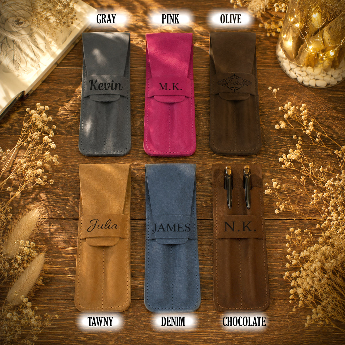 Six personalized pen pouches in different colors are arranged in a 2x3 grid on a wooden surface with dried flowers and warm string lights. The top row shows gray, pink, and olive options labeled GRAY, PINK, and OLIVE, with the names Kevin, M.