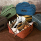 Collection of variously colored toiletry bags with visible brand names on a wooden surface.