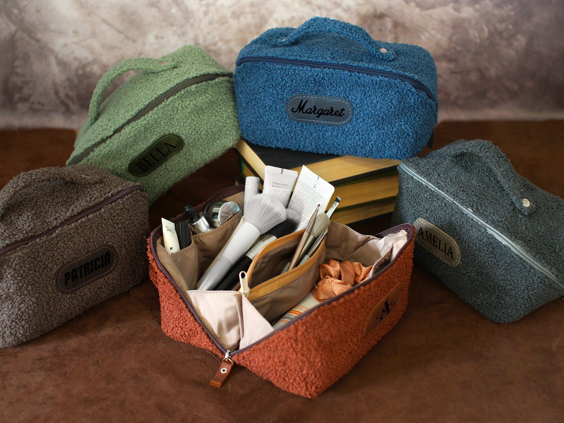 Collection of variously colored toiletry bags with visible brand names on a wooden surface.