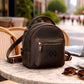 Multiple leather mini backpacks with monogram initials on textured surface