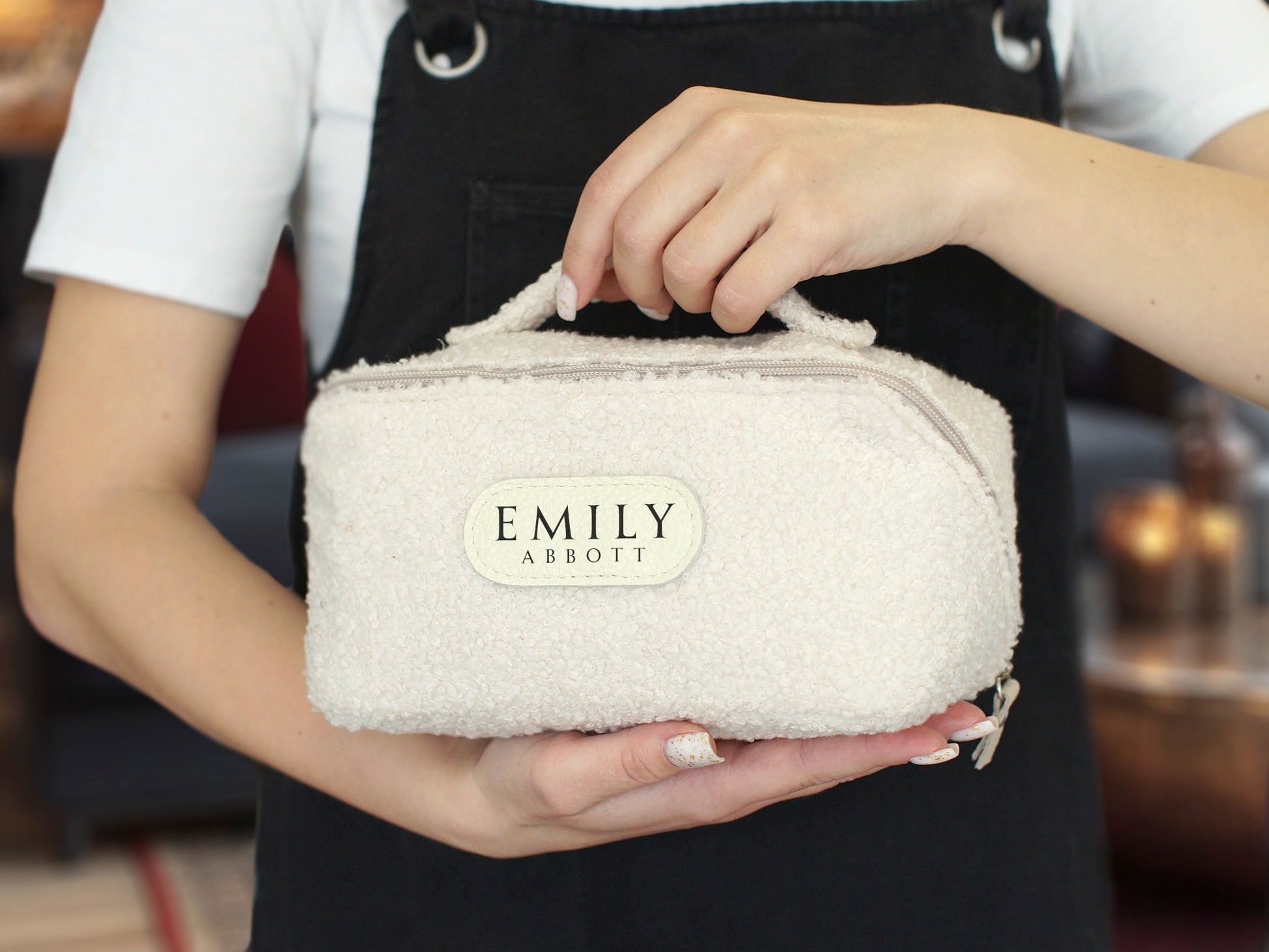 Person holding a textured pouch with 'EMILY ARBOUD' branding.