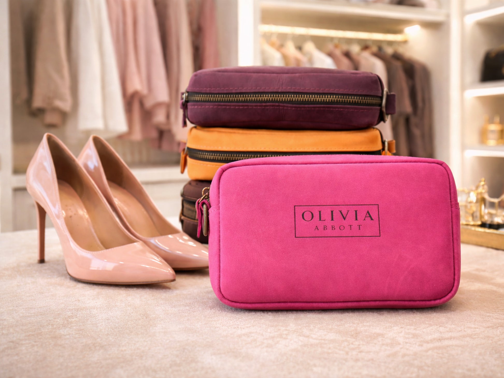 Pink crossbody bag with 'Olivia' branding next to high heels in a clothing store setting