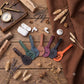 Six personalized leather keychains shaped like musical instruments (guitar, mandolin, violin, cello, trumpet, and clarinet) in various colors, displayed on a rustic wooden table with a white wireless earbud charging case, white AirPods, a brass pocket watch, dried wheat, and a brown fabric backdrop.