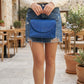 Leather structured handbag with flap closure, side profile view