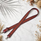 Striped leather strap with floral decorations on a marble surface
