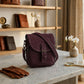 Purple bag on a marble surface with a wooden shelf in the background