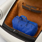 Blue duffel bag in the trunk of a vintage car with a brown interior.