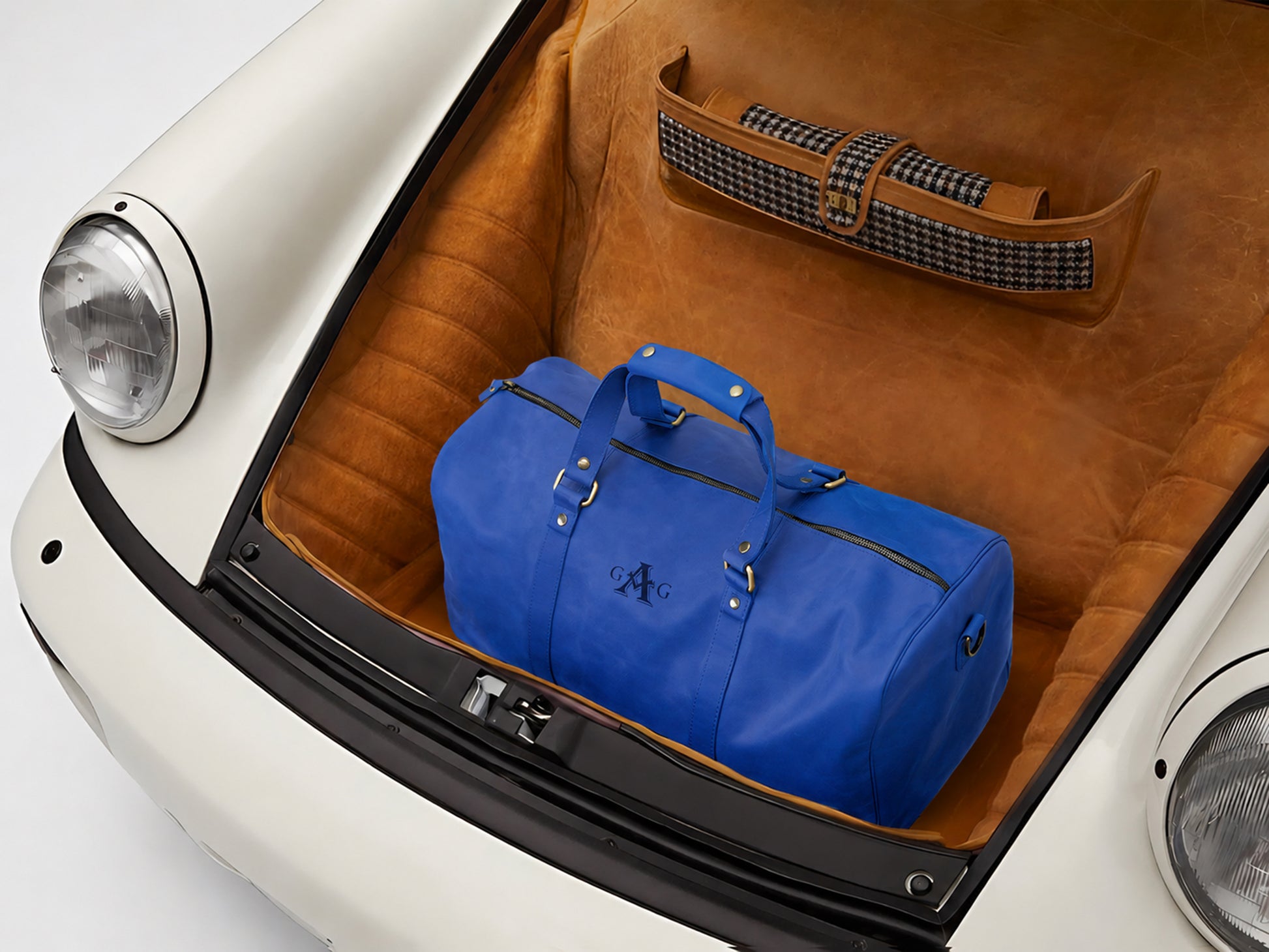 Blue duffel bag in the trunk of a vintage car with a brown interior.