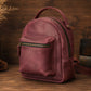 Small burgundy backpack on a wooden surface with a rustic background