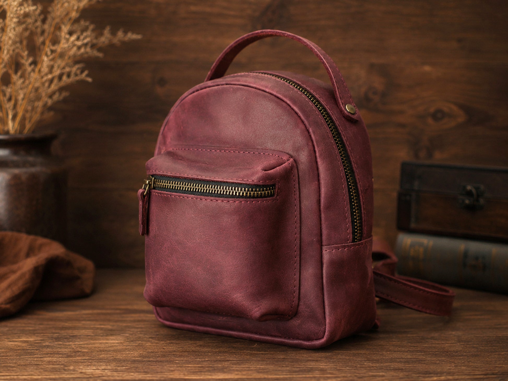 Small burgundy backpack on a wooden surface with a rustic background