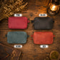 Four rectangular crossbody phone bags arranged in a 2x2 grid on a rustic wooden surface, labeled PINK, BLACK, DENIM, and RED. The bags are shown in different colors with vintage props including a lantern, dried flowers, and leather items around them.