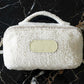White textured pouch with a beige label on a black marble background