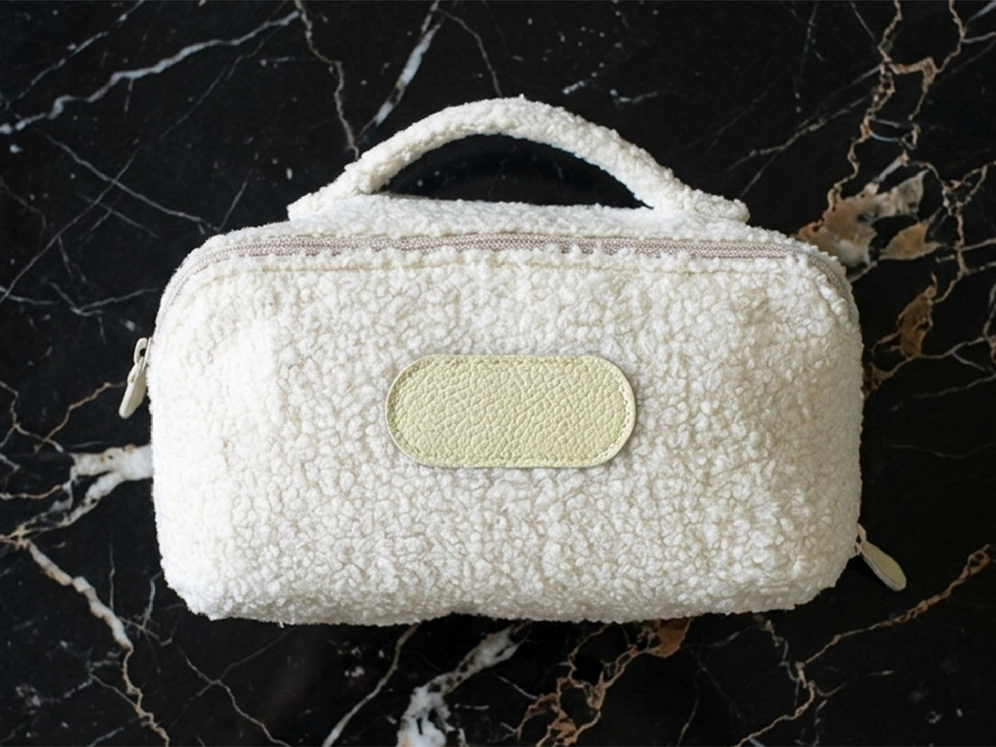 White textured pouch with a beige label on a black marble background