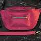Pink waist bag on a black marble surface with phone and wallet