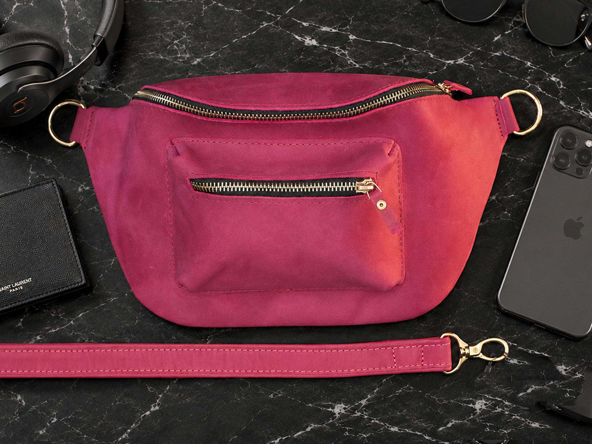 Pink waist bag on a black marble surface with phone and wallet