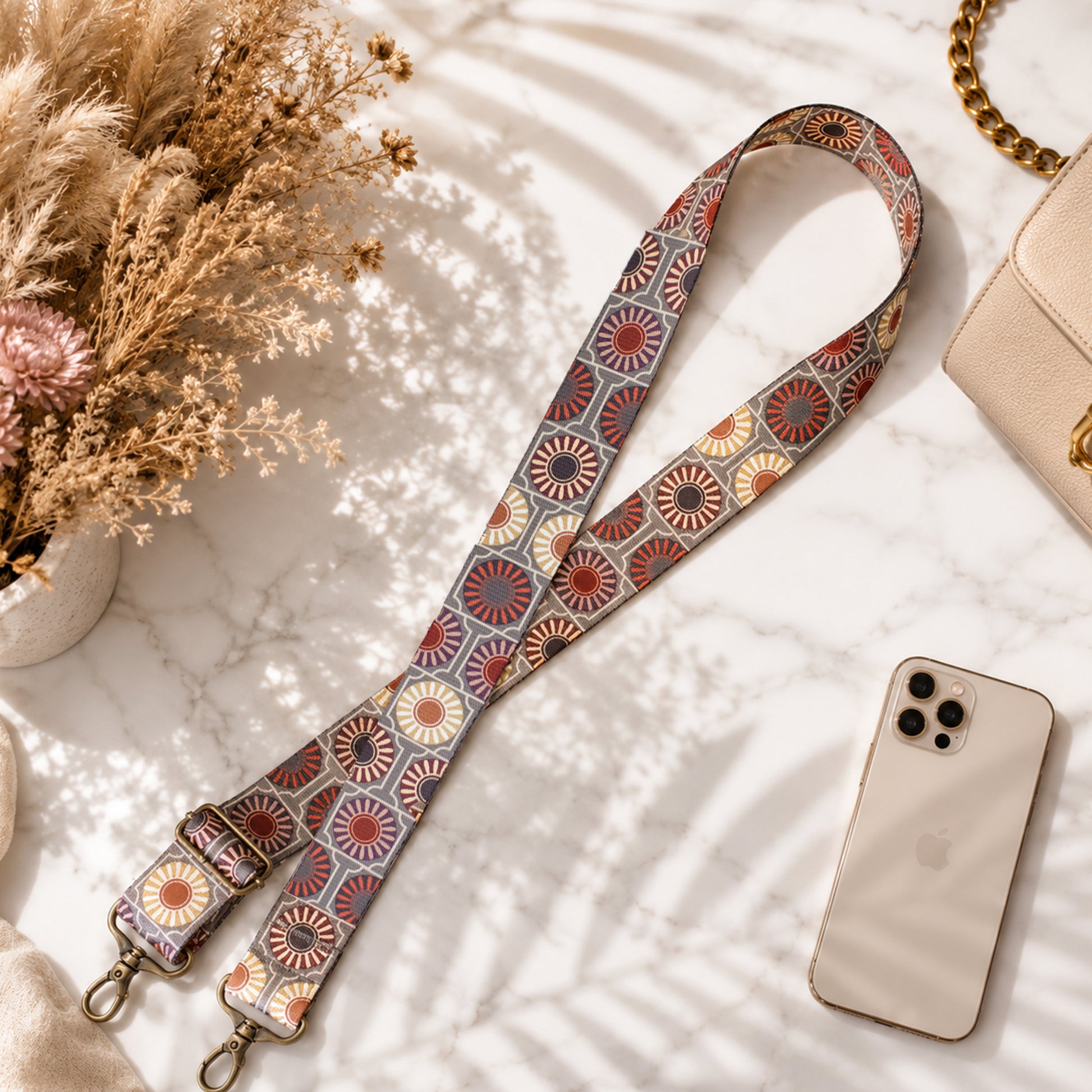 Patterned strap with a phone and flowers on a marble surface