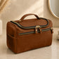 Brown leather toiletry bag on a bathroom counter with decorative elements.