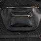 Black leather handbag with gold zipper on a dark surface
