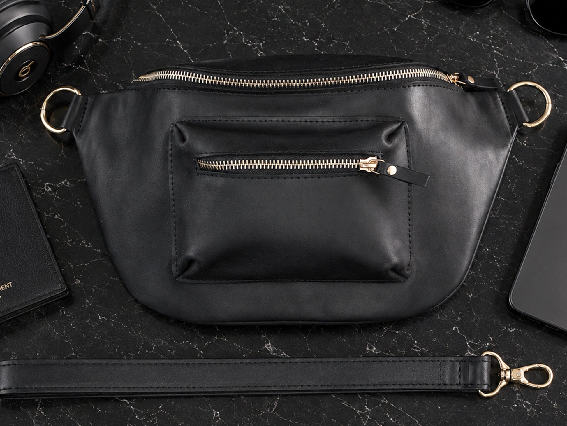 Black leather handbag with gold zipper on a dark surface
