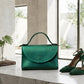 Green handbag and high heels on a marble surface with a neutral background