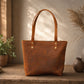 Brown leather tote bag on a wooden surface with decorative plants and vases in the background