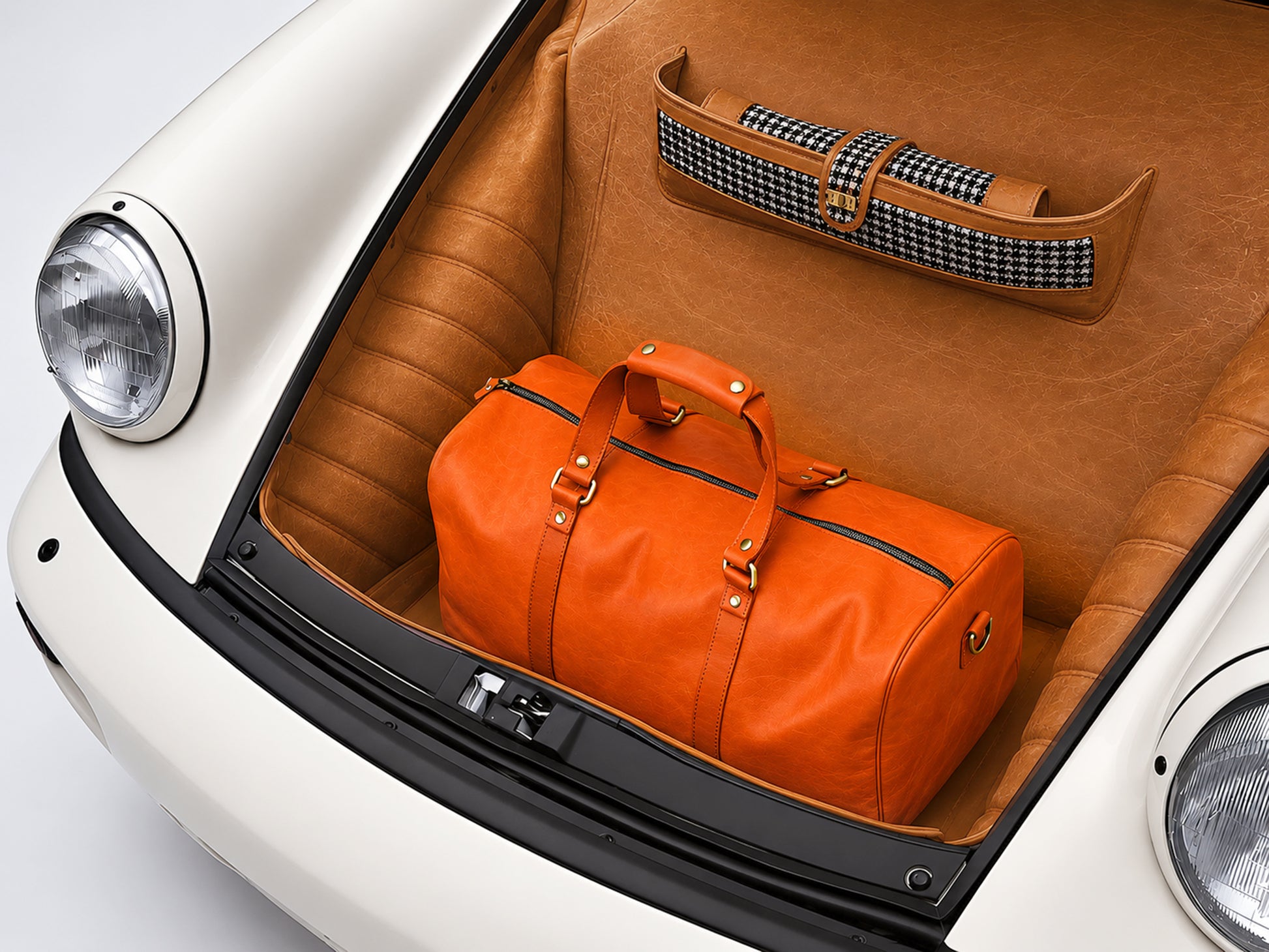 Orange duffel bag in a car trunk with a white background