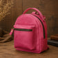 Pink backpack on a wooden surface with books and a vase in the background