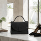 Black handbag and high heels on a marble surface with a neutral background