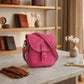 Pink satchel bag on a marble surface with decorative items in the background