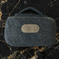 Dark gray textured pouch with a brown patch on a black marble background