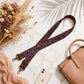 Leopard print strap with gold hardware on a marble surface with a handbag and phone.