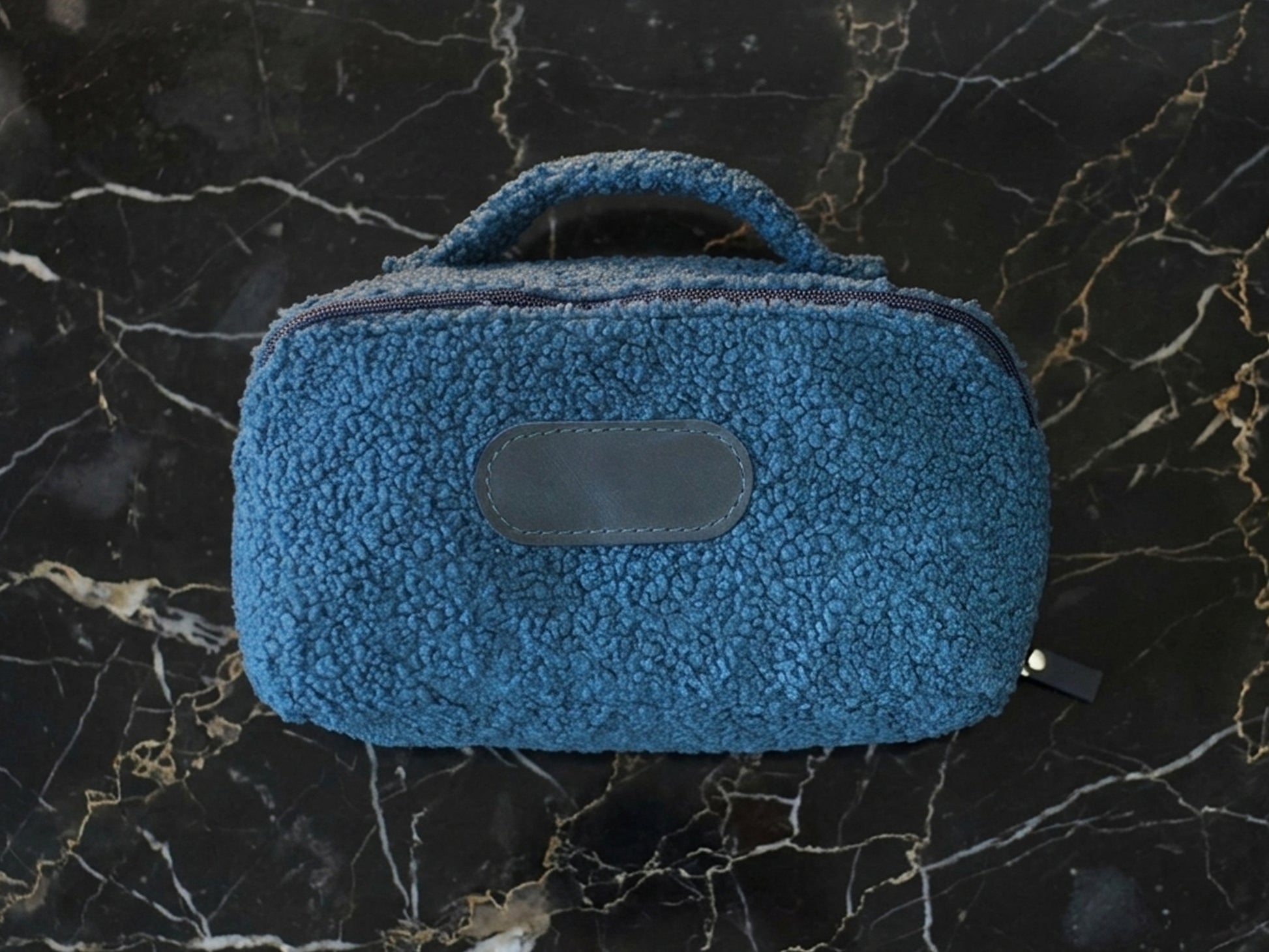 Blue textured pouch on a black marble surface