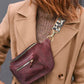 Person wearing a beige coat with a purple leather bag over their shoulder.