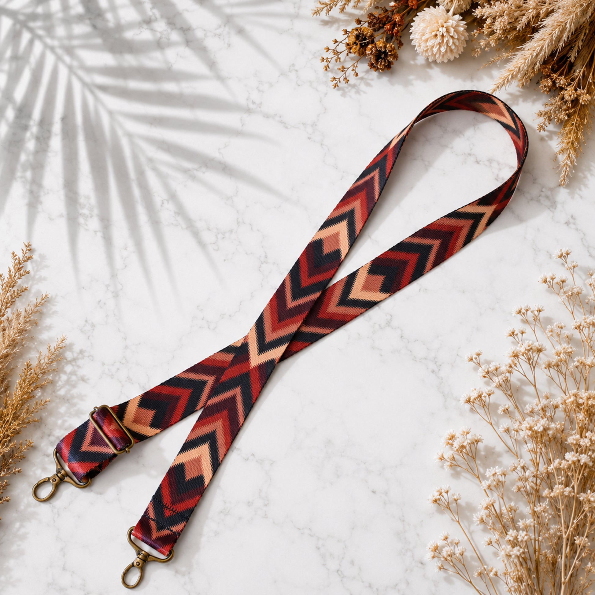Patterned strap with gold hardware on a light surface with dried plants