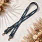 Blue leather strap with cut-out design on a light surface with dried flowers.