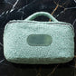 Green textured handbag on a black marble surface