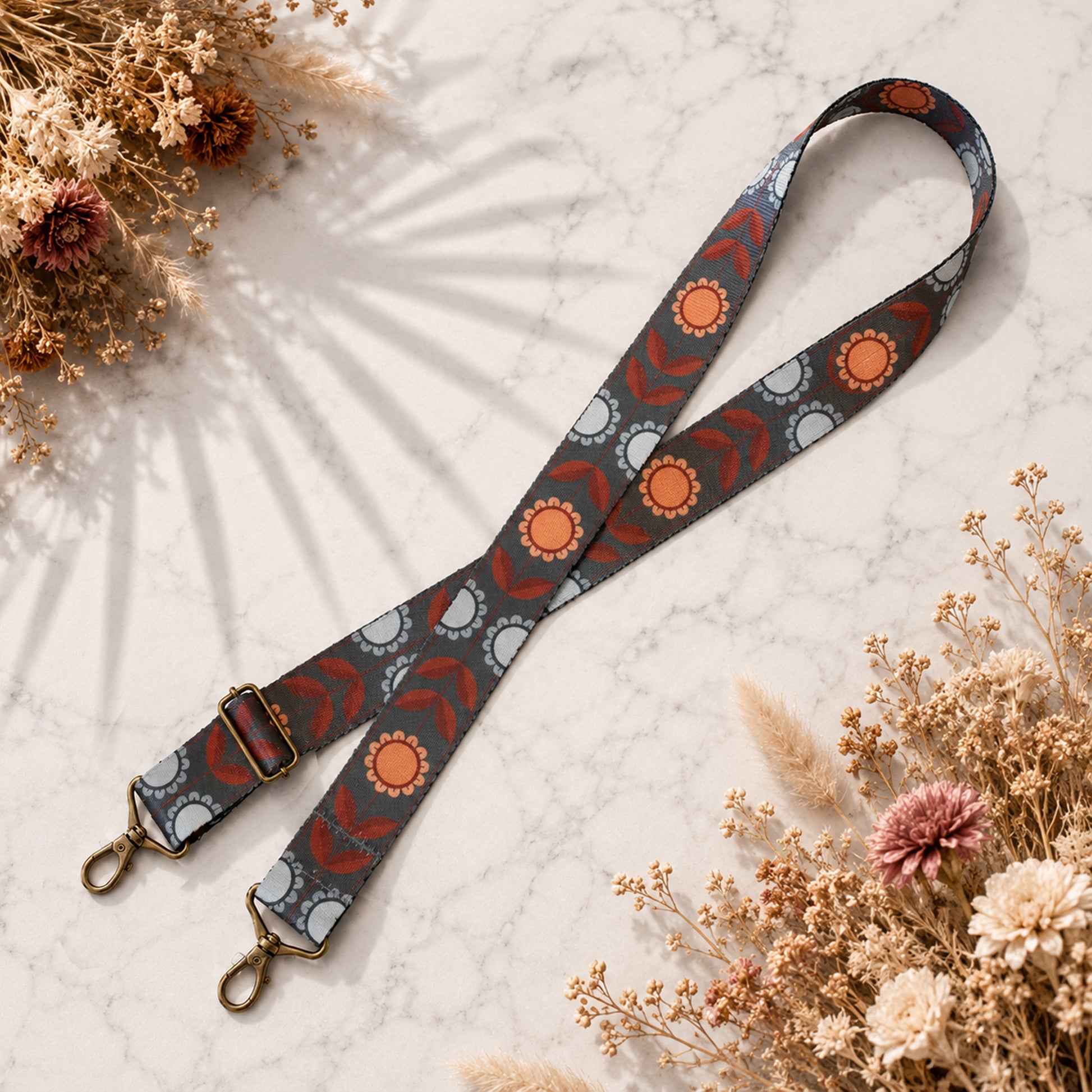 Decorative strap with floral pattern on a marble surface with dried flowers.