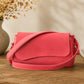 Pink handbag on a wooden surface with decorative elements in the background