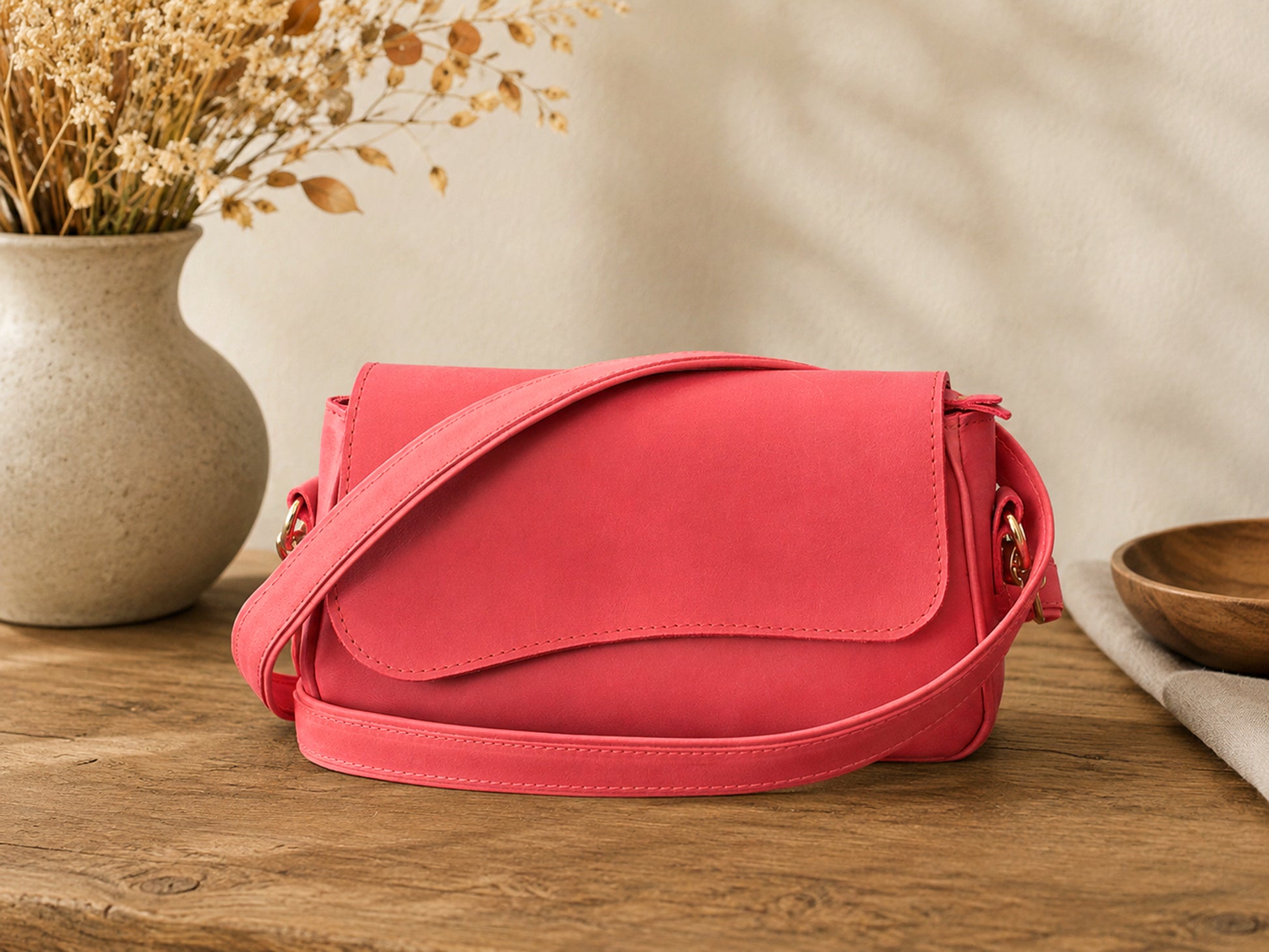 Pink handbag on a wooden surface with decorative elements in the background