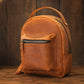 Brown leather backpack on a wooden surface with a dark brown background