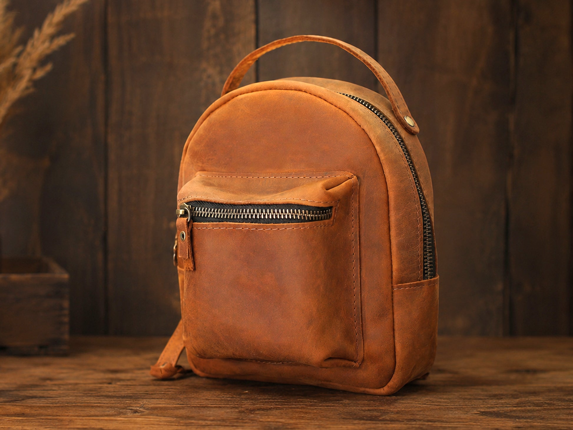 Brown leather backpack on a wooden surface with a dark brown background