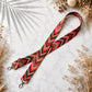 Red and black patterned strap on a light surface with dried plants
