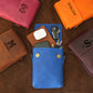 Collection of leather pouches in various colors with monogramming on a brown surface.