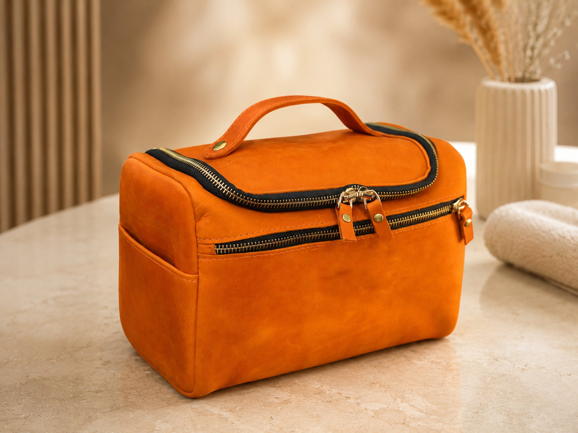Orange cosmetic bag with gold zipper on a beige surface