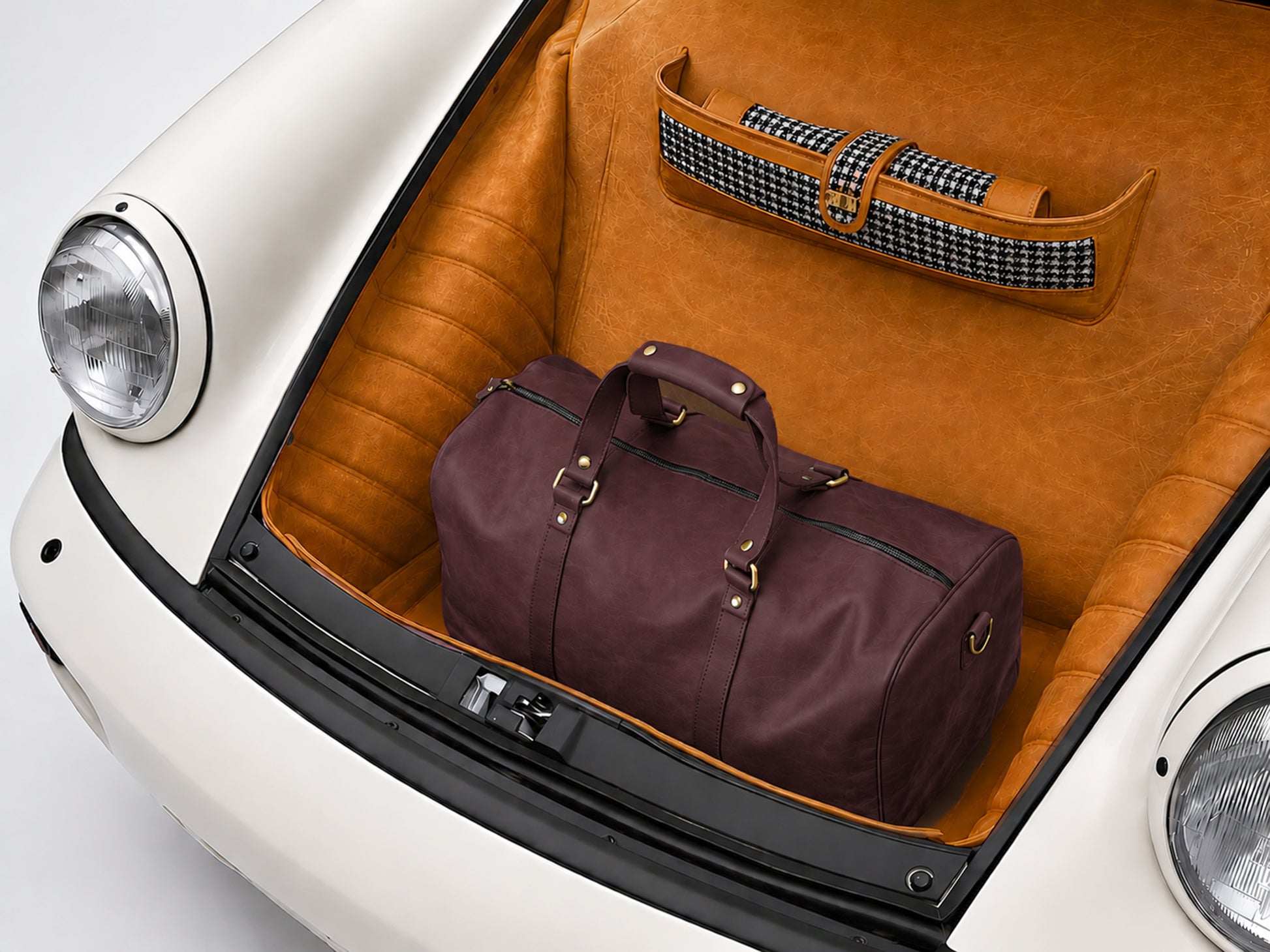 Brown leather duffel bag in a car trunk with a checkered cover.